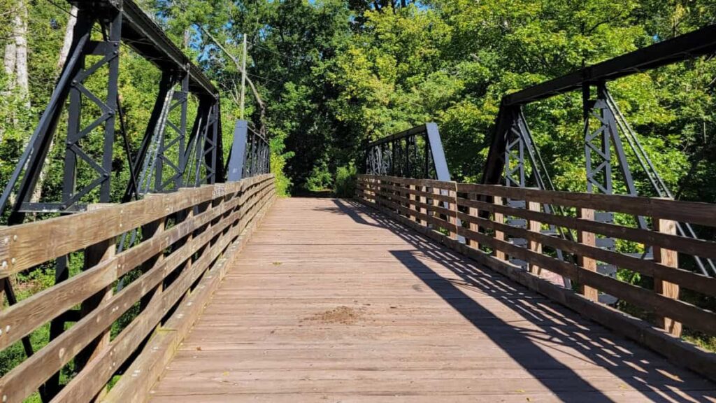 a wooden bridge with black metal railings crosses into Evansburg State Park