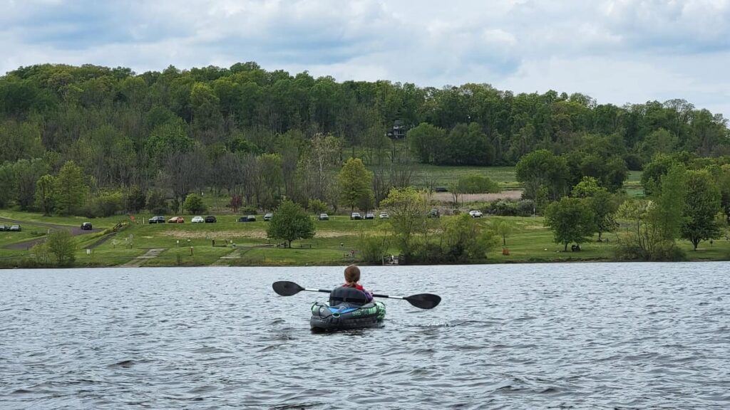 a young girl paddles a kayak in Lake Galena at Peace Valley Park