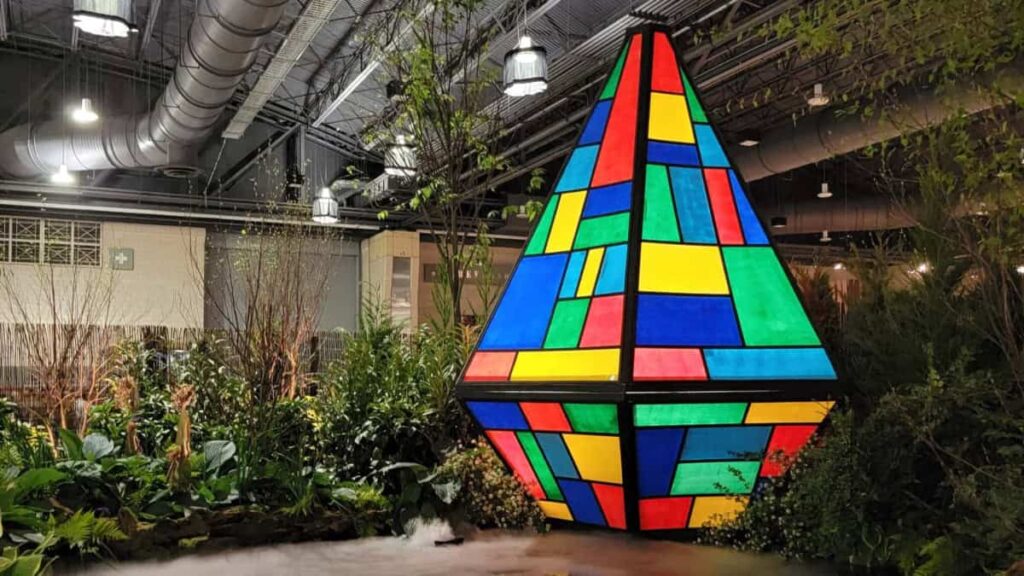 A large colorful sculpture sits among plants at the Philadelphia flower show
