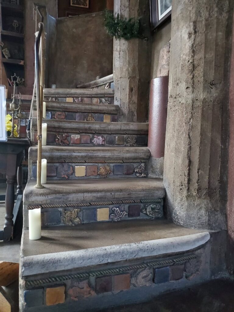 Concrete steps with tiles on the risers are lined with candles and have a metal handrail