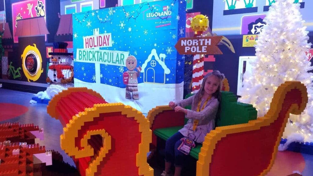 A young girl sits in a life sized LEGO Duplo sled at Legoland Discovery Center