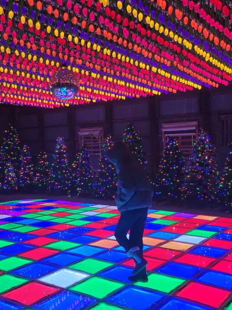 A girl dances on a light up dance floor with glowing tulips above