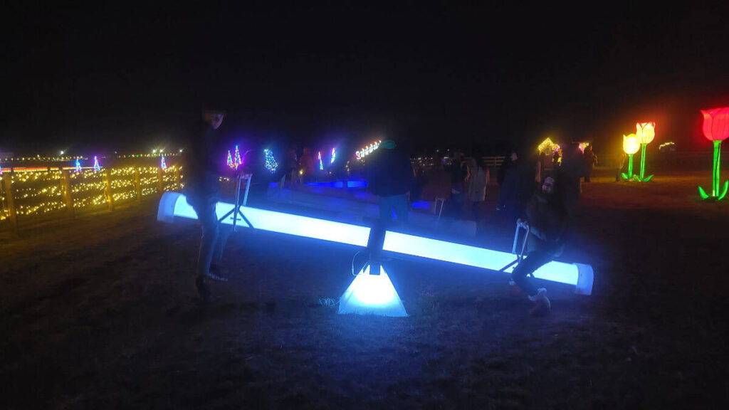 kids sit on a light up seesaw at night at Holland Ridge Farms