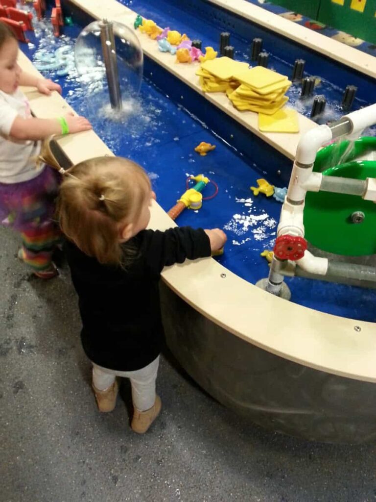 A small child reaches into a water play table at Giggleberry Fair in Peddler's Village