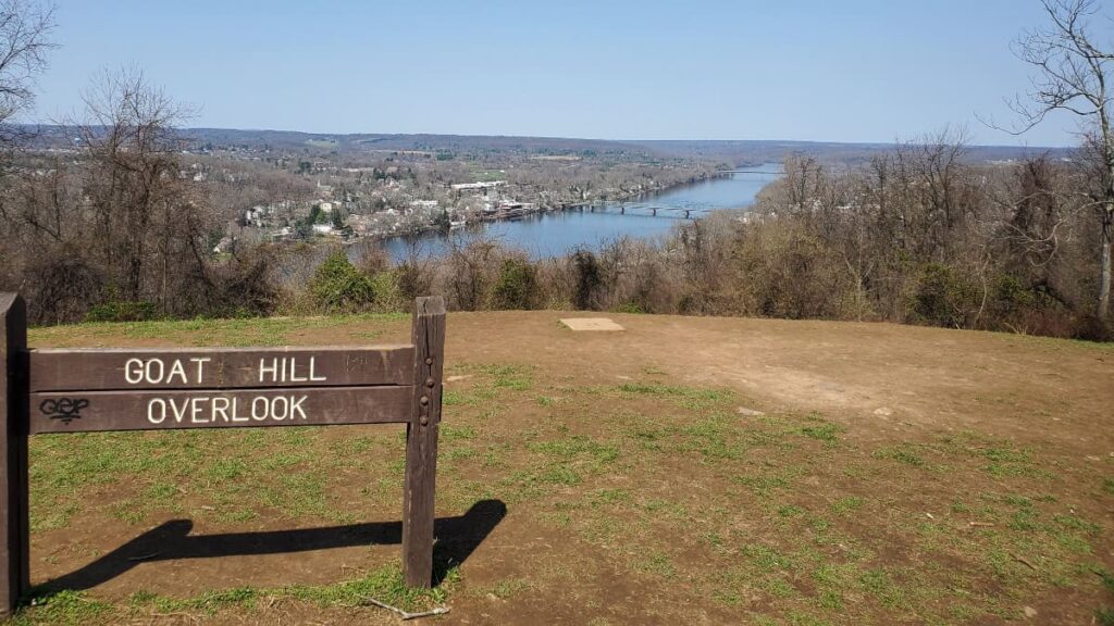 A sign at the top of a hill overlooking the Delaware River reads "Goat Hill Overlook"