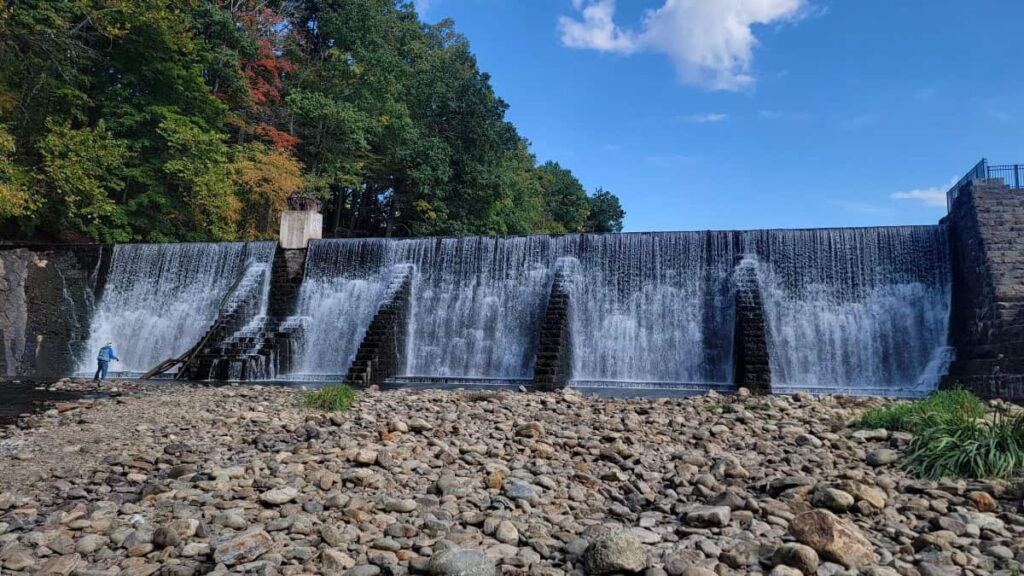 A large dam creates a pretty waterfall with stones at the bottom