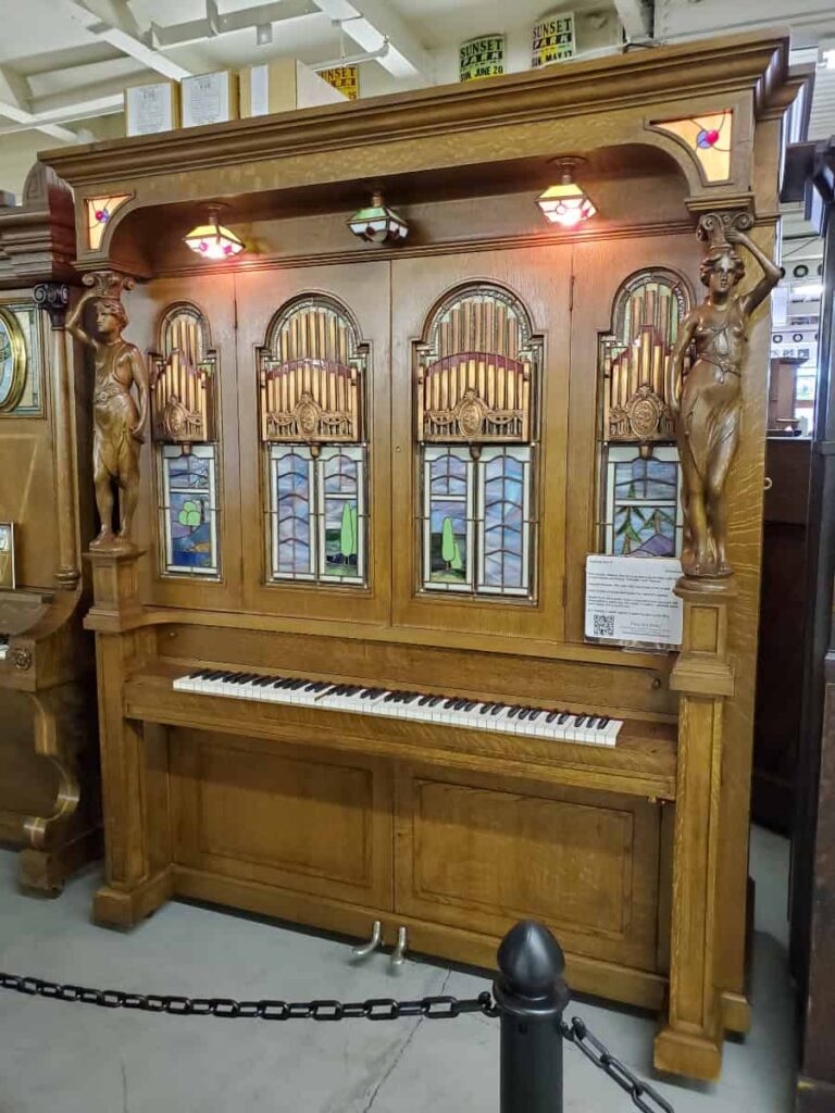 A self playing piano sits behind a chain at the American Treasure Tour Museum