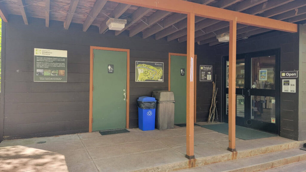looking at two bathroom doors on the outside walll fo the bowmans hill wildflower preserve vsitor center